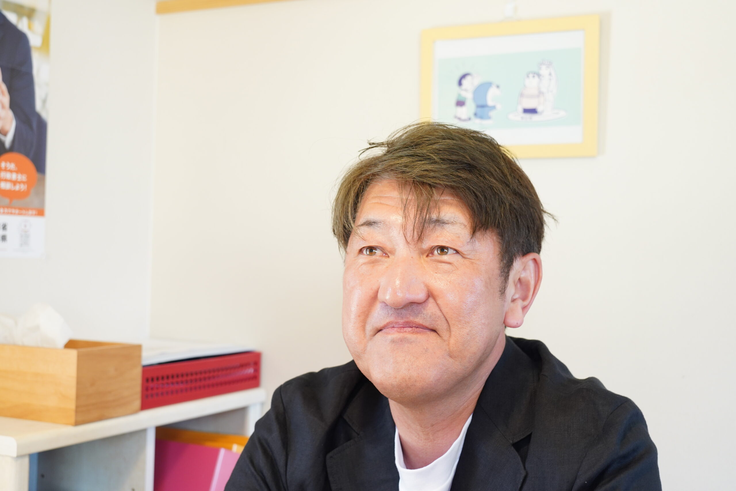 行政書士の男性がジャケット着用し斜め上を見て笑顔の様子